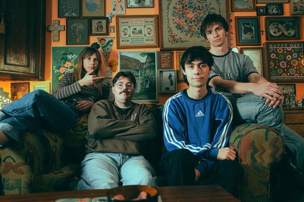 Adelaide indie pop band The Tullamarines posing together on a couch in a cozy room with framed art on the wall.